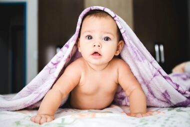 baby under baby blanket with name